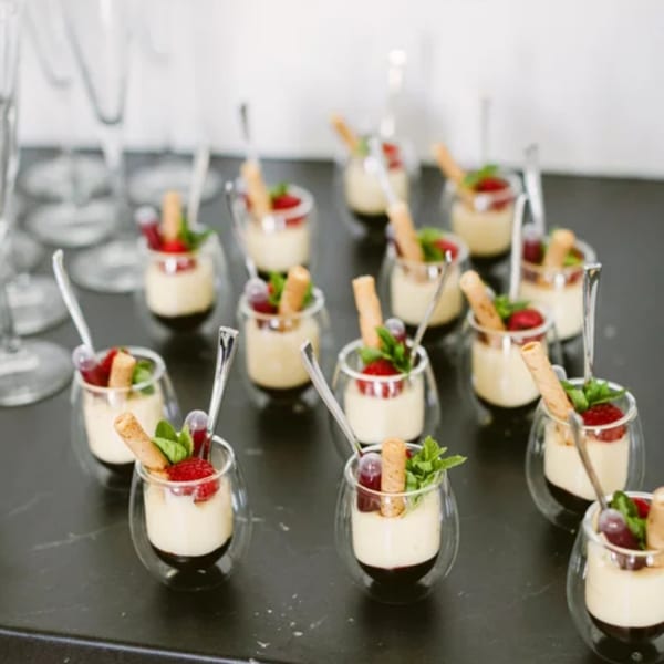 Rows of individual Notch 8 desserts in small glasses with berries, mint, and wafer cookies.