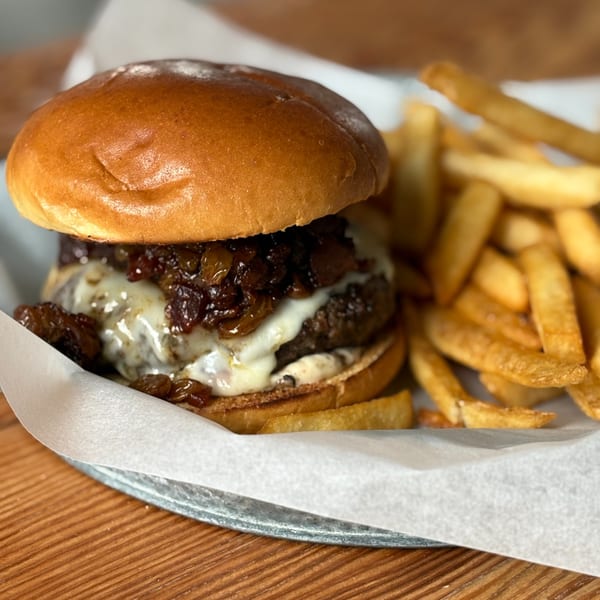 Notch 8's American burger with caramelized onions and melted cheese, served with golden fries.