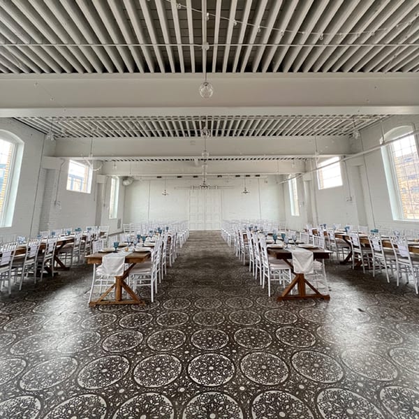 A large, empty Notch 8 dining hall with long wooden tables, white chairs, and patterned floor.